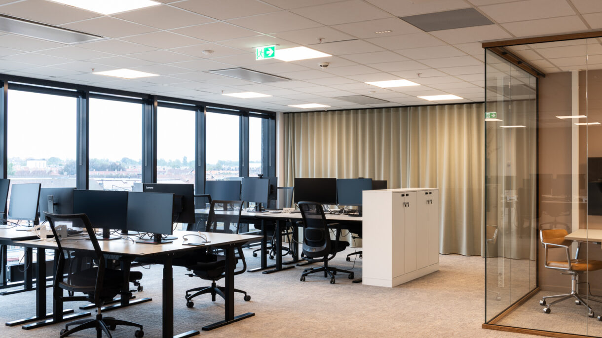 Åpent kontorlandskap med arbeidsplasser etter rehabilitering.